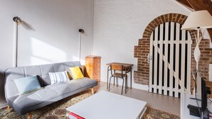 Un salon comprenant un canapé, une table basse, un meuble en bois, un bureau et une lampe.