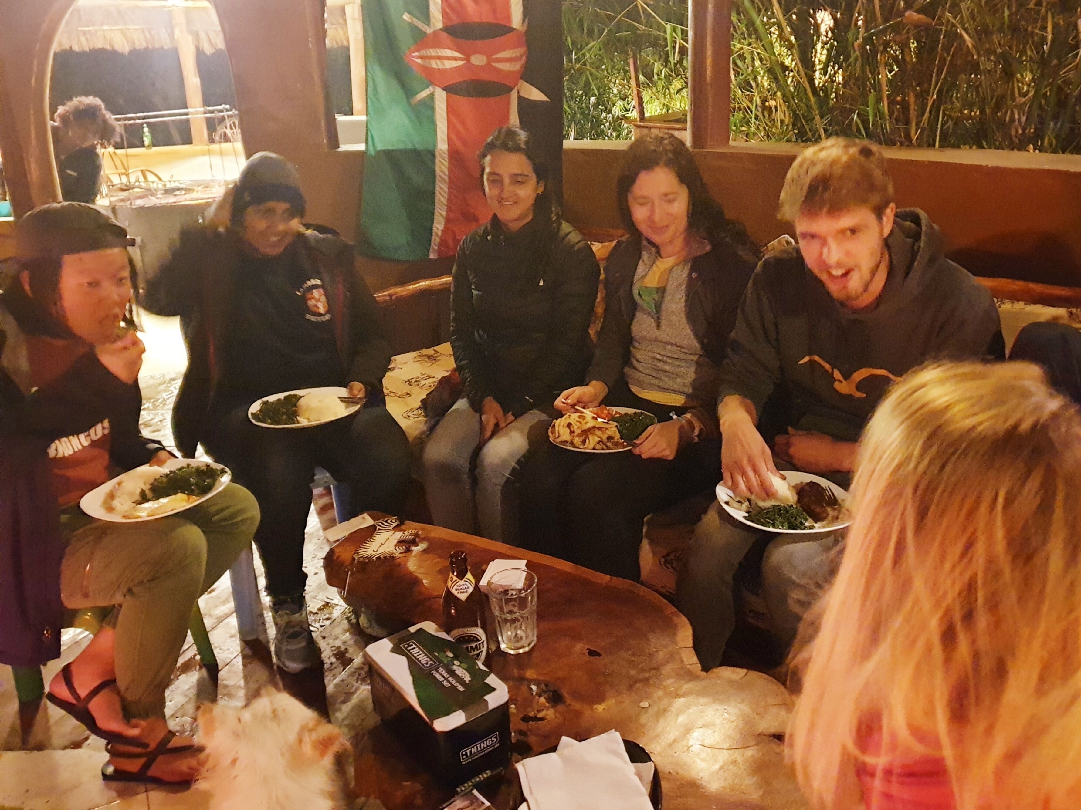 Un grupo de personas sentadas en un sofá, comiendo y bebiendo.