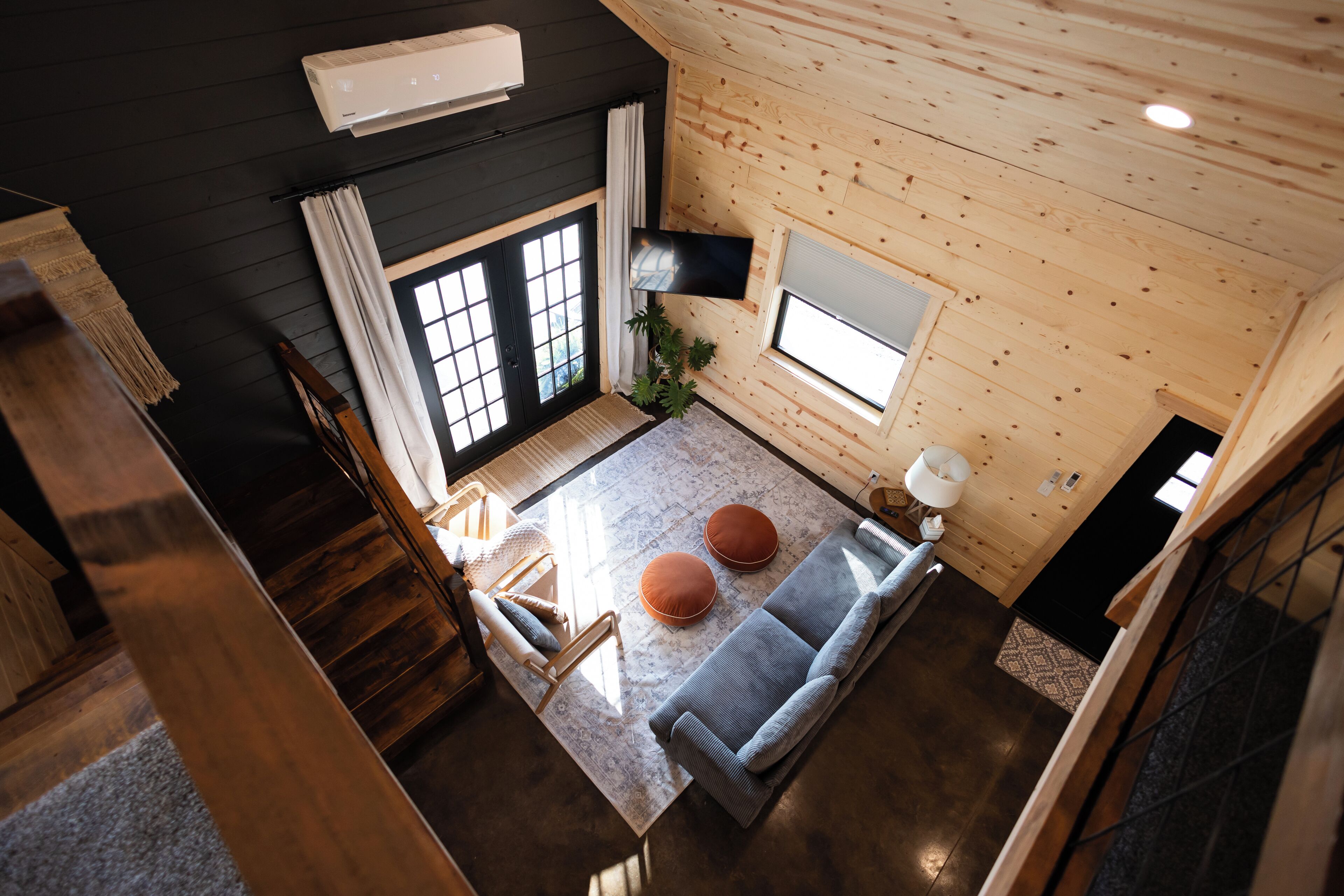 Een modern interieur met een houten plafond, een bank, een eettafel en een aan de muur bevestigde televisie.