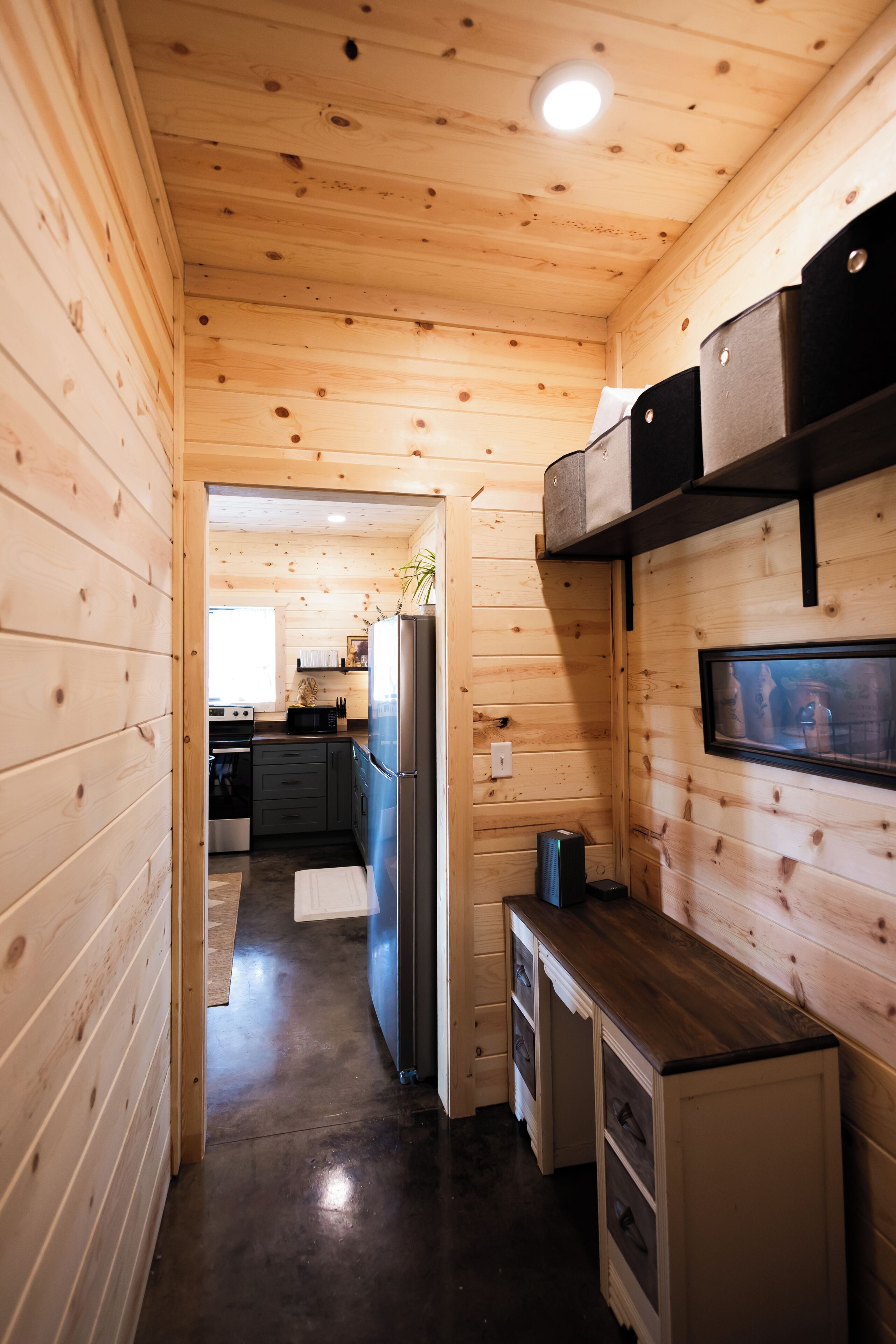 Un interior de madera con una zona de cocina, que incluye armarios, un refrigerador y un microondas.