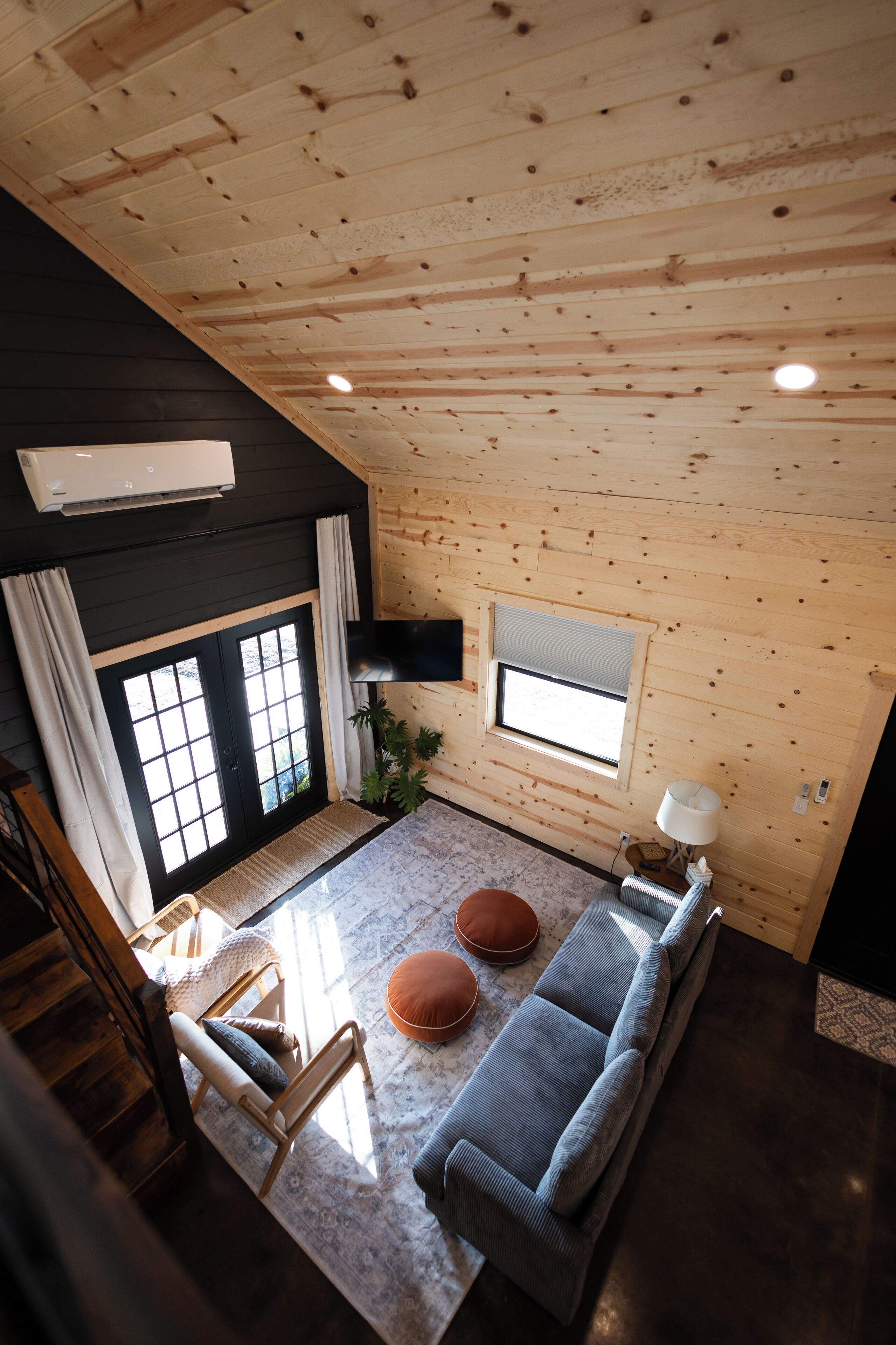 A cozy wooden cabin interior with a sofa, a chair, a small table, and a window.