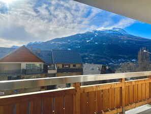 Un balcon offrant une vue sur une montagne et les bâtiments environnants.