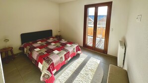 Een slaapkamer met een bed, nachtkastje, raam en uitzicht.