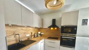 Een moderne keuken met houten werkbladen, roestvrijstalen apparatuur en witte kastjes.