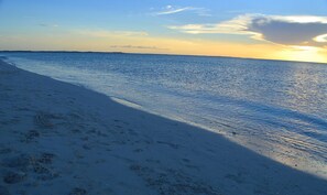 A beach with a clear sky and calm sea. - Ground Floor Yacht Club Condo E1 - Sunset Views, BBQ, Walk to Beach and Dining (Providenciales)