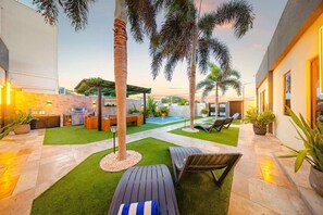 A modern outdoor patio with a pool, lounge chairs, and a barbecue area. - New Sea La Vie Suite # 5 |2BR|1BR W. Pool&Jacuzzi (Noord)
