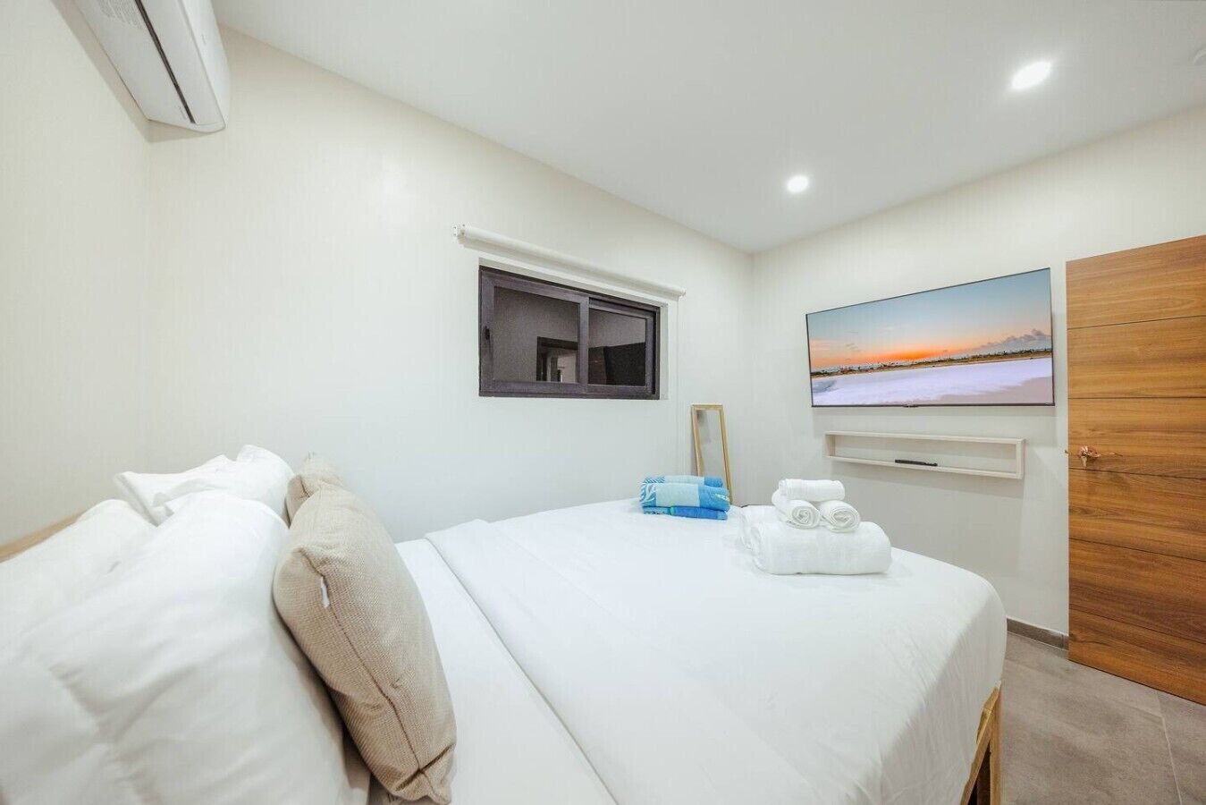 Ein Hotelzimmer mit einem Bett, einem Fenster, einem Flachbildfernseher und einer Holztür.