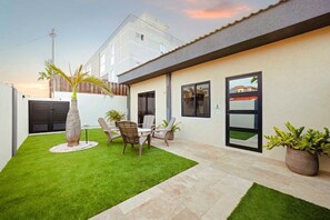 Et moderne hus med en patio, spiseplads og garage.