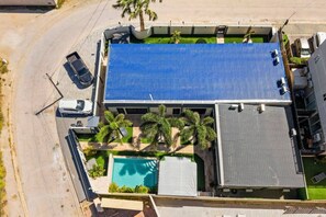 En boligbygning med blå tag, swimmingpool og parkeringsområde.