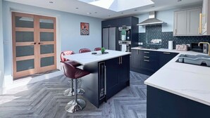 A modern kitchen with a central island, dark cabinetry, and a large window above the island. - 6 Bedroom Victorian Townhouse in Central Harrogate (Harrogate)