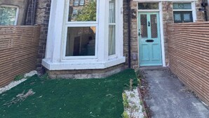A two-story townhouse with a bay window, a front door, and a small front yard with artificial grass. - 6 Bedroom Victorian Townhouse in Central Harrogate (Harrogate)