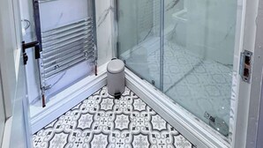 A modern bathroom with a glass shower enclosure, a chrome towel rack, and patterned floor tiles. - 6 Bedroom Victorian Townhouse in Central Harrogate (Harrogate)
