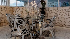 Un coin repas avec une table en verre, un tapis à motifs zébrés et un mur en pierre.