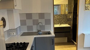 Kompakti keittiö, jossa on kaasuliesi, pesuallas ja laatoitettu välitila.
