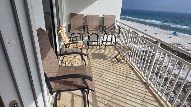 A balcony with outdoor seating, a view of the beach, and a white railing. - Beachfront Perdido Key Condo | Private Balcony (Pensacola)