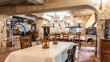 Un'area pranzo rustica con pareti in pietra, arredi in legno e un camino.