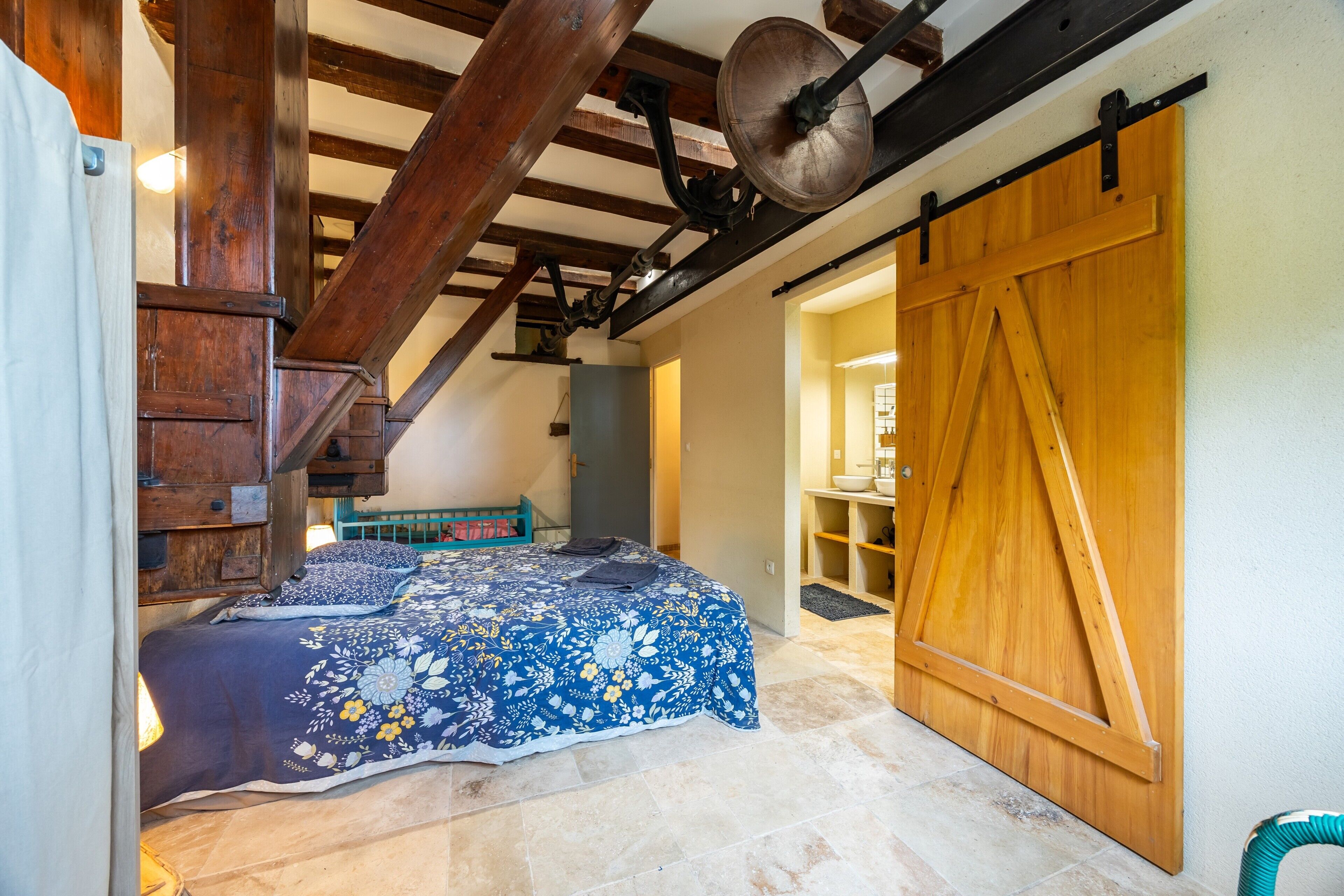 Ein Schlafzimmer mit einem Bett, Holzbalken, Deckenventilator und einer Schiebetür im Bauernhausstil.