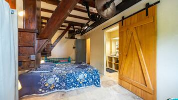 Ein Schlafzimmer mit einem Bett, Holzbalken, Deckenventilator und einer Schiebetür im Bauernhausstil.