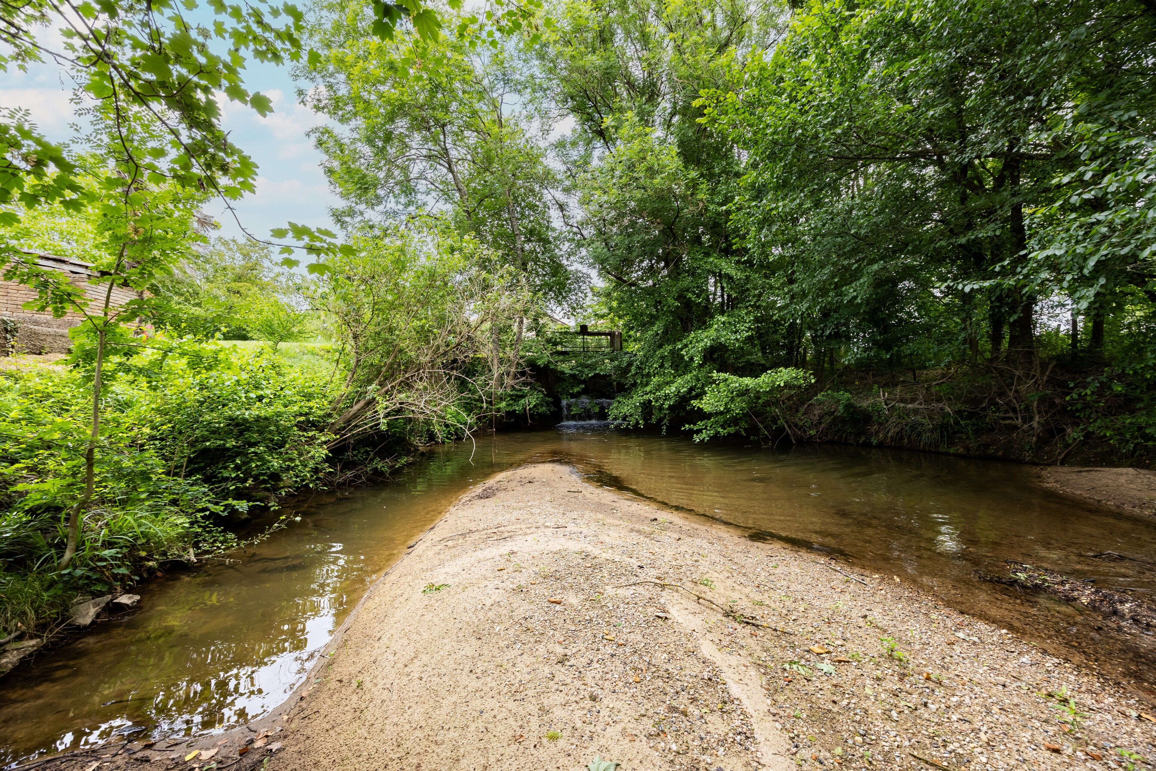 Une rivière traversée par un pont, entourée d’une végétation luxuriante.