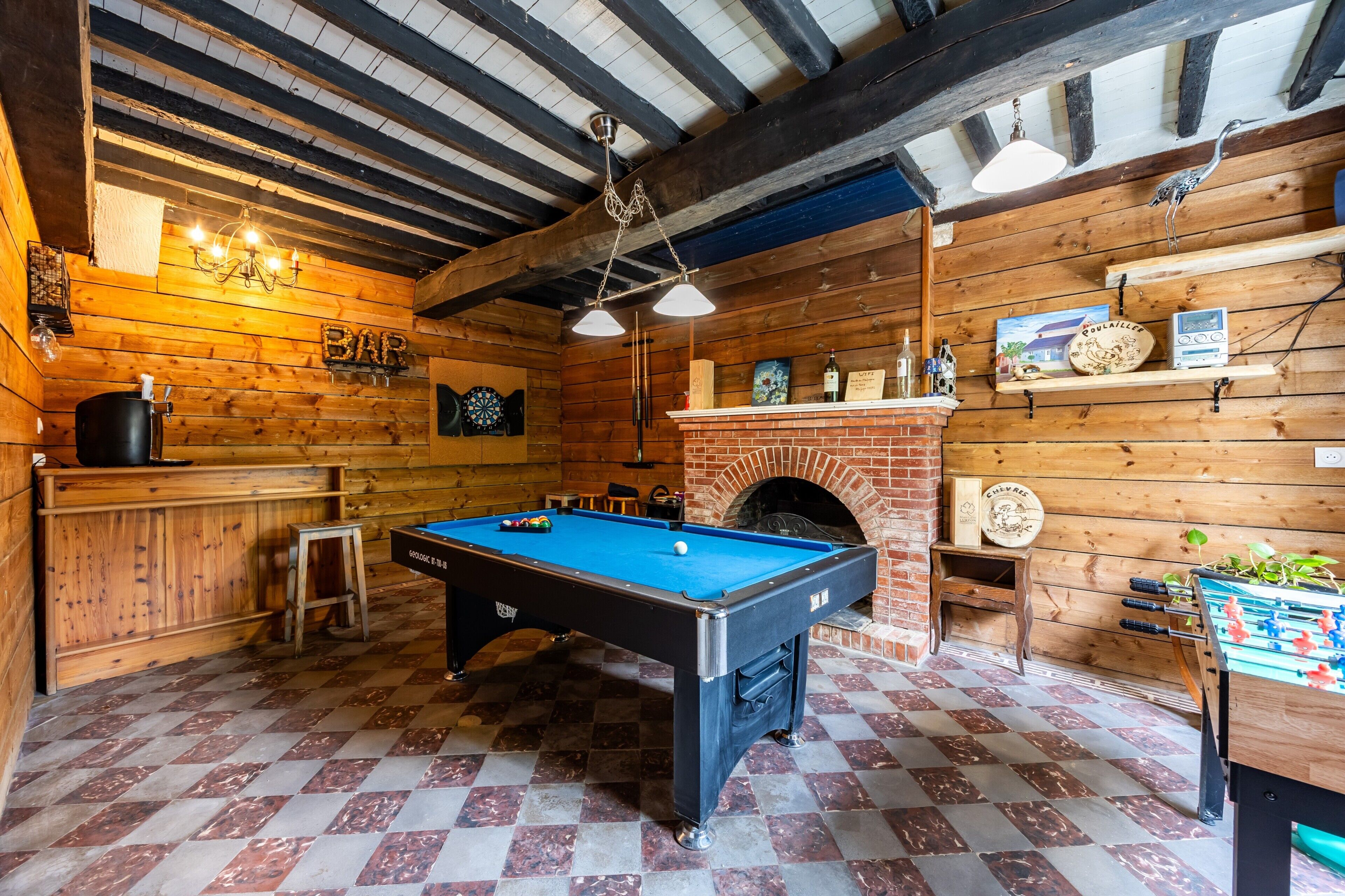 Un tavolo da biliardo, un tavolo da calcio, un caminetto e un'area bar in una stanza in legno.