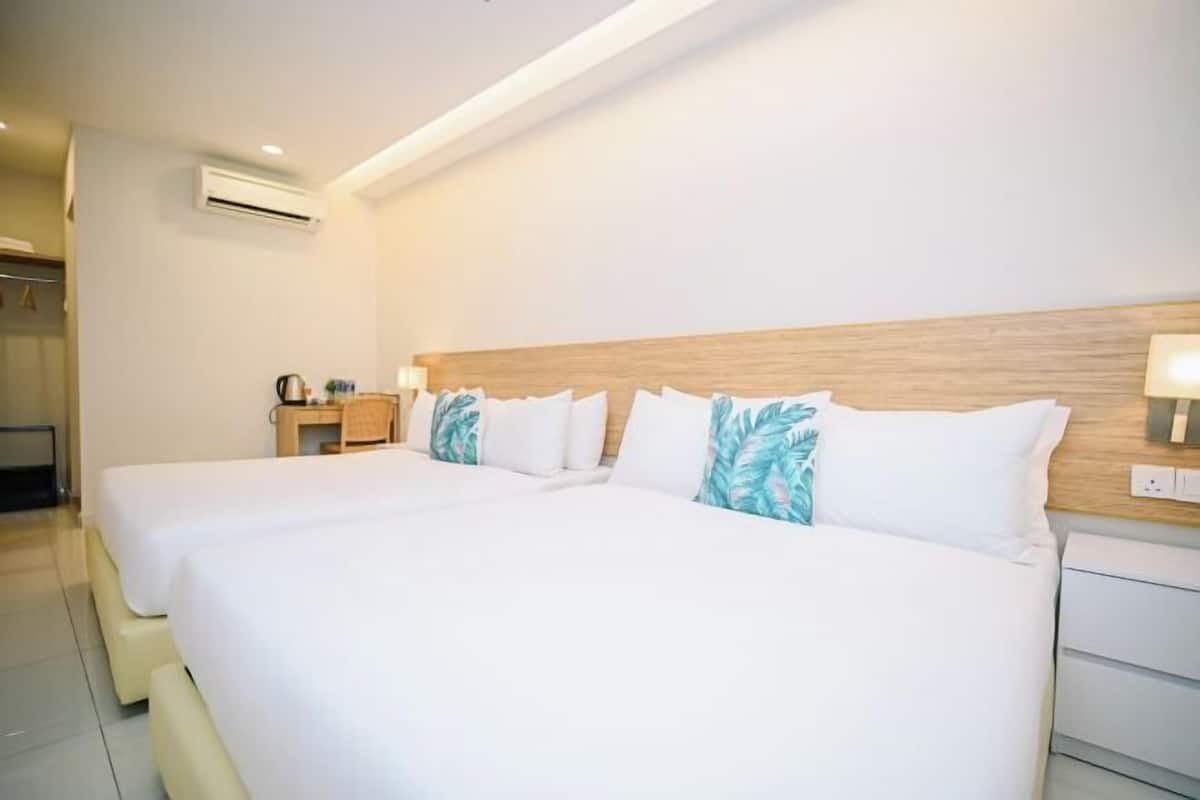 Ein Hotelzimmer mit einem großen Bett, einem Nachttisch, einer Lampe und einer Klimaanlage.
