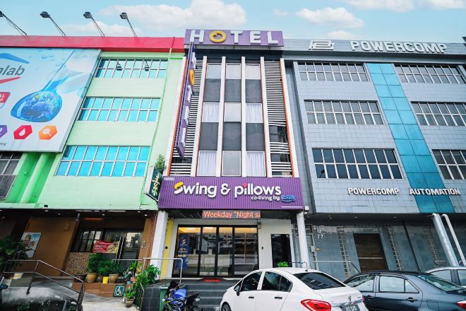 A hotel with a sign for 'Swing & Pillows' and 'Powercomp Automation' on the facade.