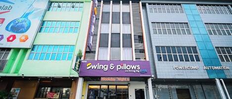 A hotel with a sign for 'Swing & Pillows' and 'Powercomp Automation' on the facade.