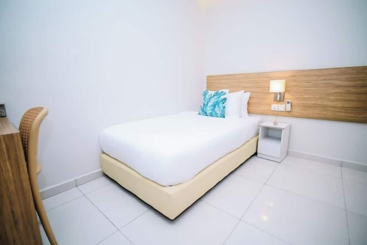 Ein Hotelzimmer mit einem Bett, einem Nachttisch, einer Lampe und einem Sessel.