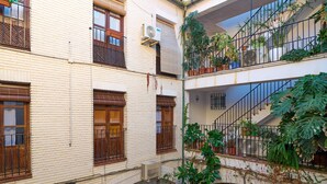 Un edificio de varios pisos con balcones, unidades de aire acondicionado y plantas en macetas.