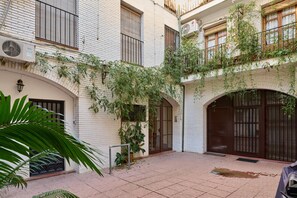 Un patio con paredes de ladrillo blanco, una reja de metal y plantas en macetas.