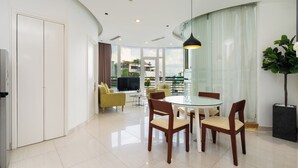 A modern living room with a glass dining table, wooden chairs, a sofa, and a TV. - VAH Ben Thanh Tower - Saigon Central (Ho Chi Minh City)