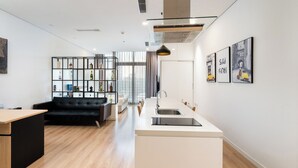 A modern kitchen with a central island, a black sofa, and a bookshelf. - VAH Ben Thanh Tower - Saigon Central (Ho Chi Minh City)