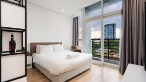 A modern hotel room with a large bed, a nightstand, a desk, and a view of the city through large windows. - VAH Ben Thanh Tower - Saigon Central (Ho Chi Minh City)
