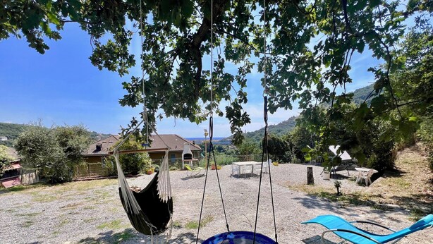 A hammock and swing set in a backyard with a view of a house and hills. - VILLA TIGULLIO (Chiavari)