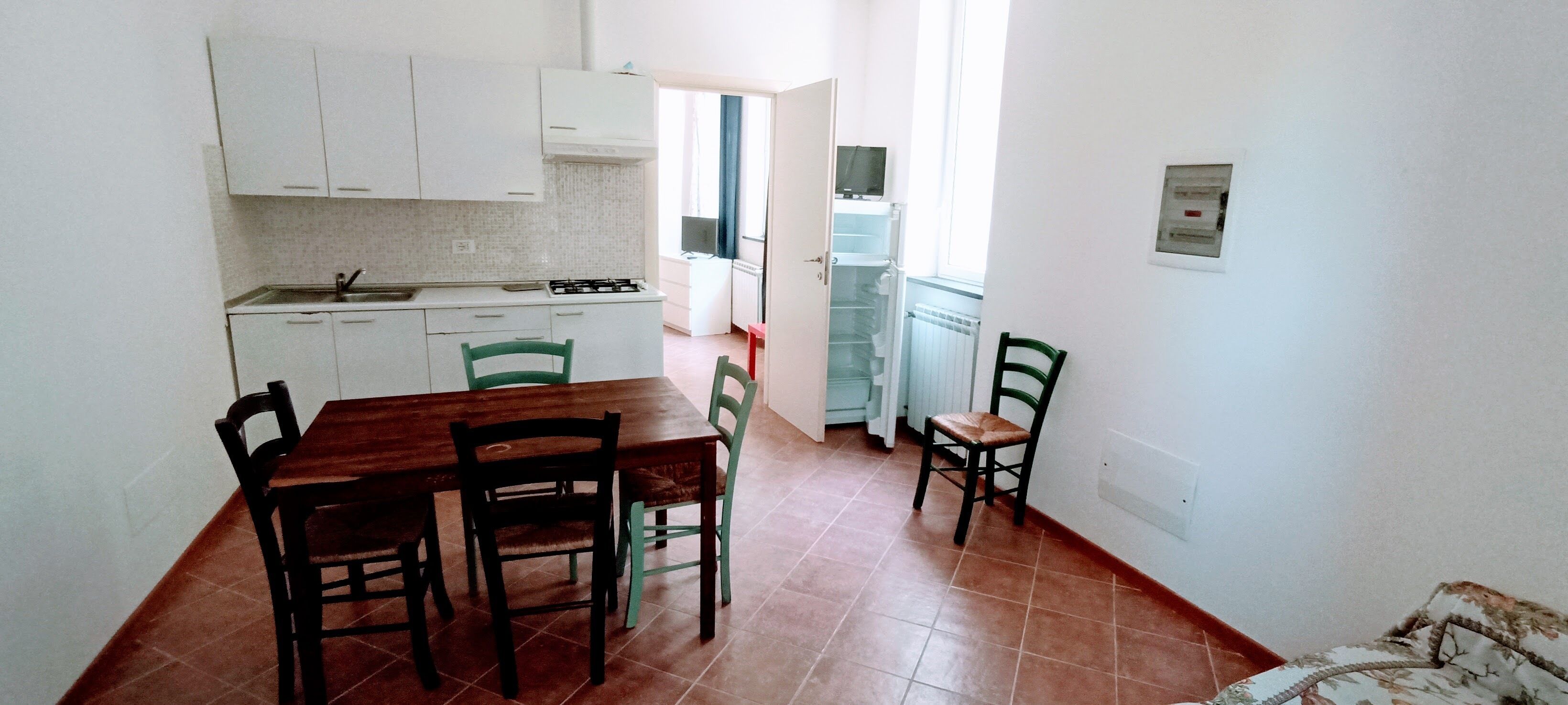 Cocina compacta con armarios blancos, una mesa de comedor de madera y sillas.