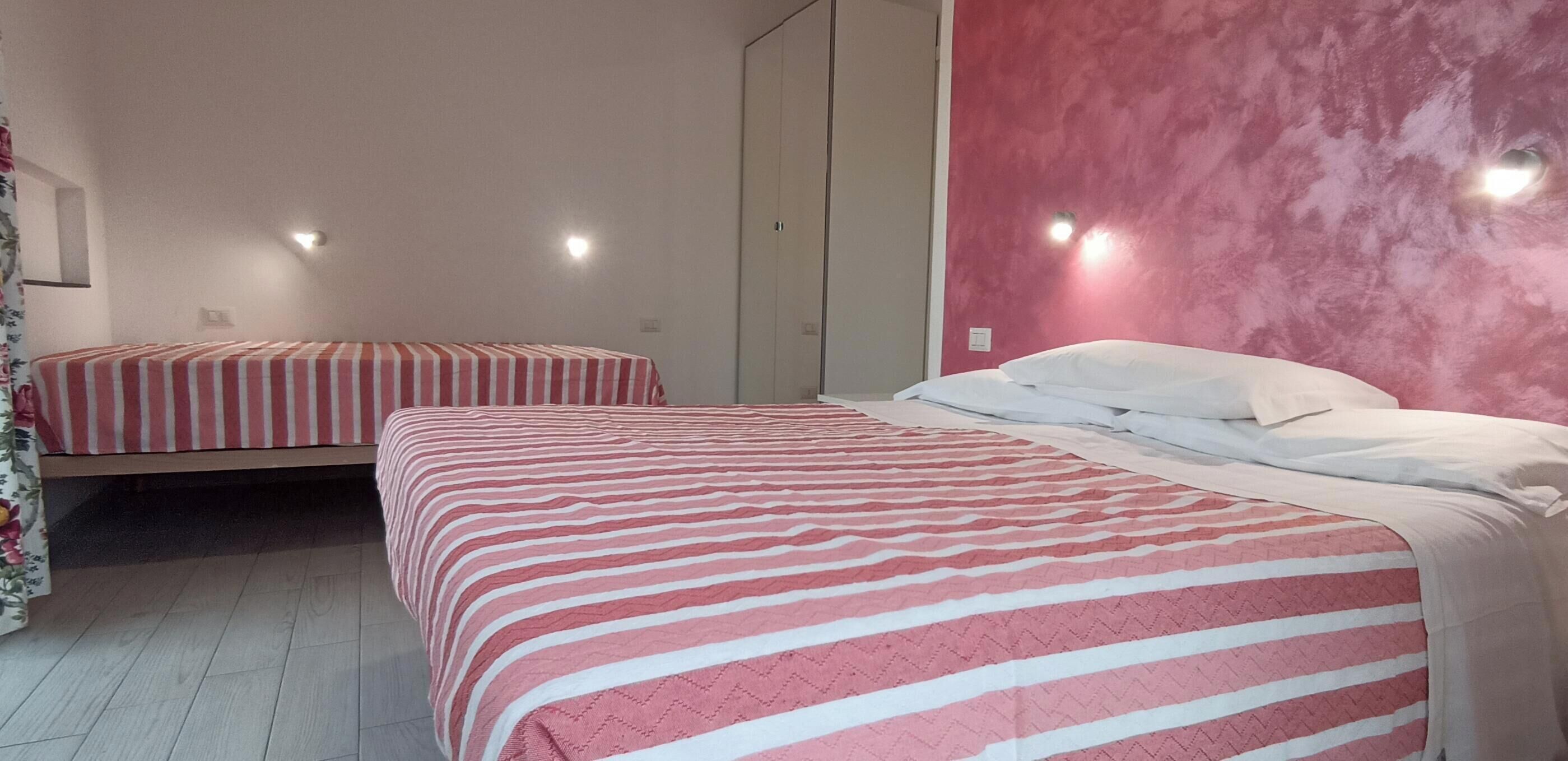Ein Zimmer mit zwei Betten, einem Kleiderschrank und einer rosafarbenen Wand.