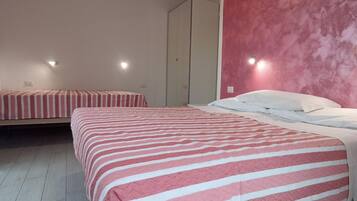 Ein Zimmer mit zwei Betten, einem Kleiderschrank und einer rosafarbenen Wand.
