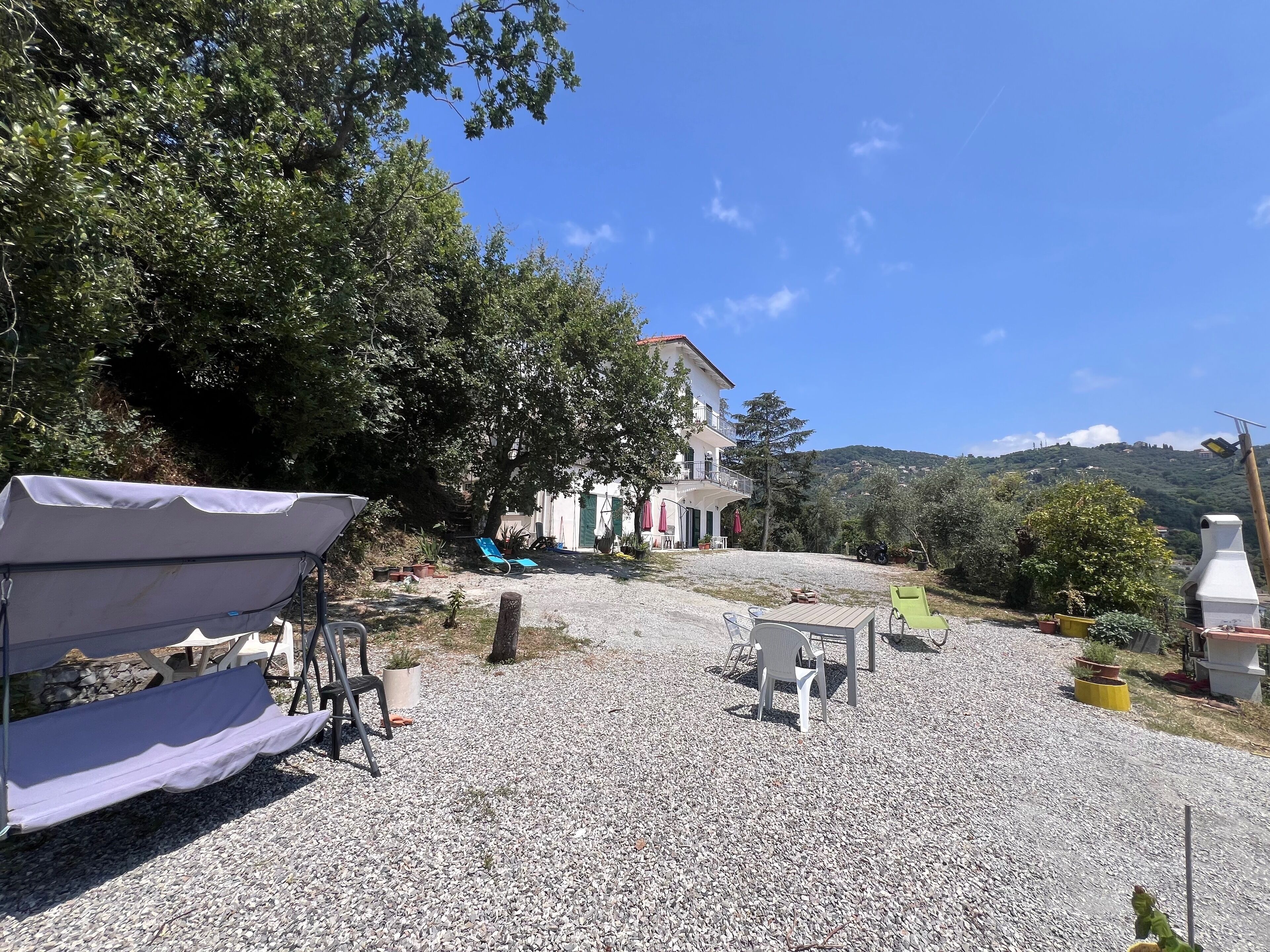 Ein Haus mit Kiesweg, Sitzgelegenheit im Freien und Blick auf einen Hügel.