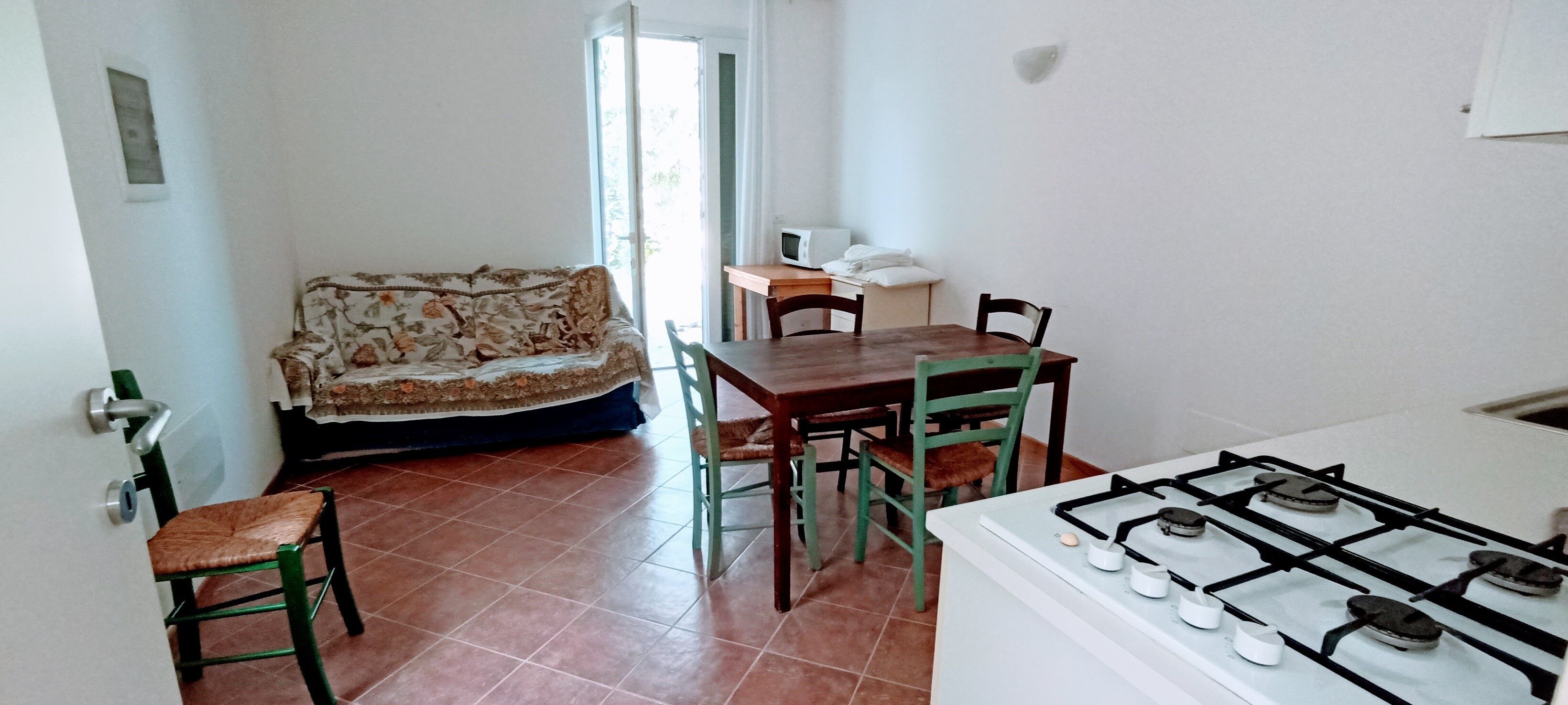 Una cucina funzionale con piano cottura a gas, un tavolo con sedie, un divano e una finestra.