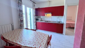 A compact kitchen with red cabinets, a microwave, and a gas stove. - VILLA TIGULLIO (Chiavari)