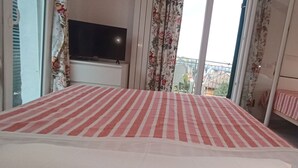 A hotel room with a bed, a TV, and a balcony with a view. - VILLA TIGULLIO (Chiavari)