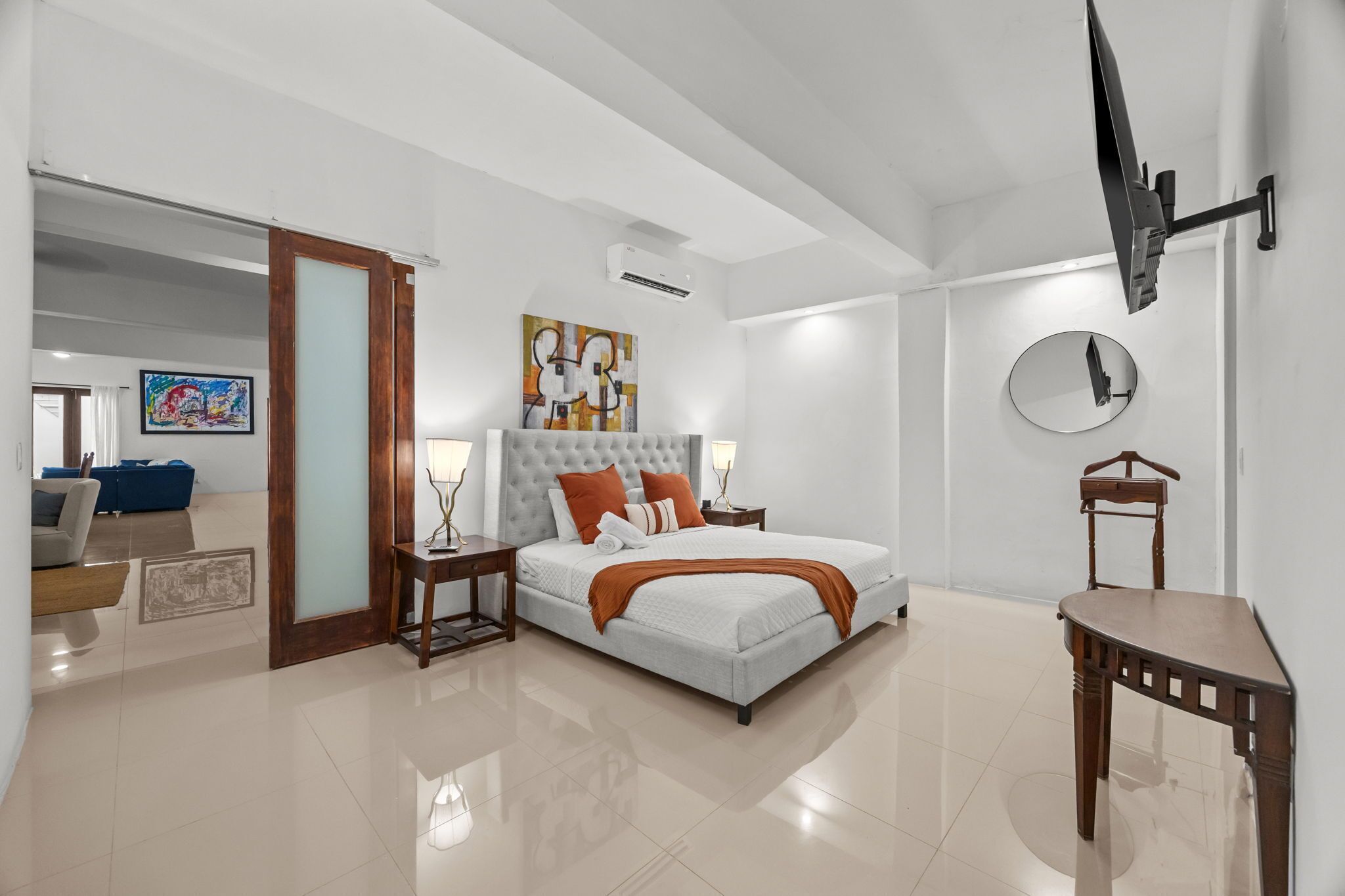 A modern bedroom with a large bed, a TV mounted on the wall, and a small table.