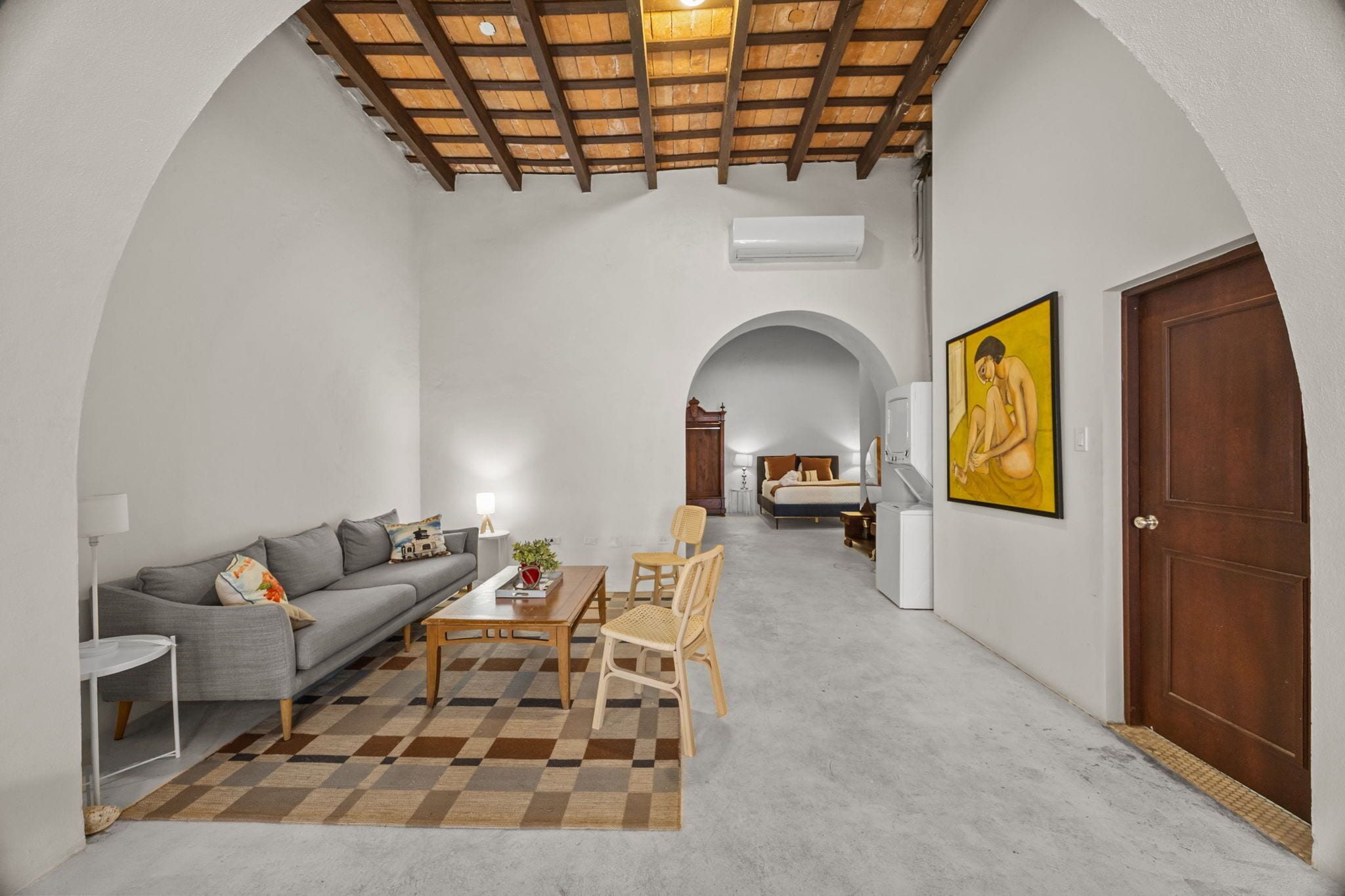 Un interior modern amb un sofà, taula de dinar, cadirees i un quadre.