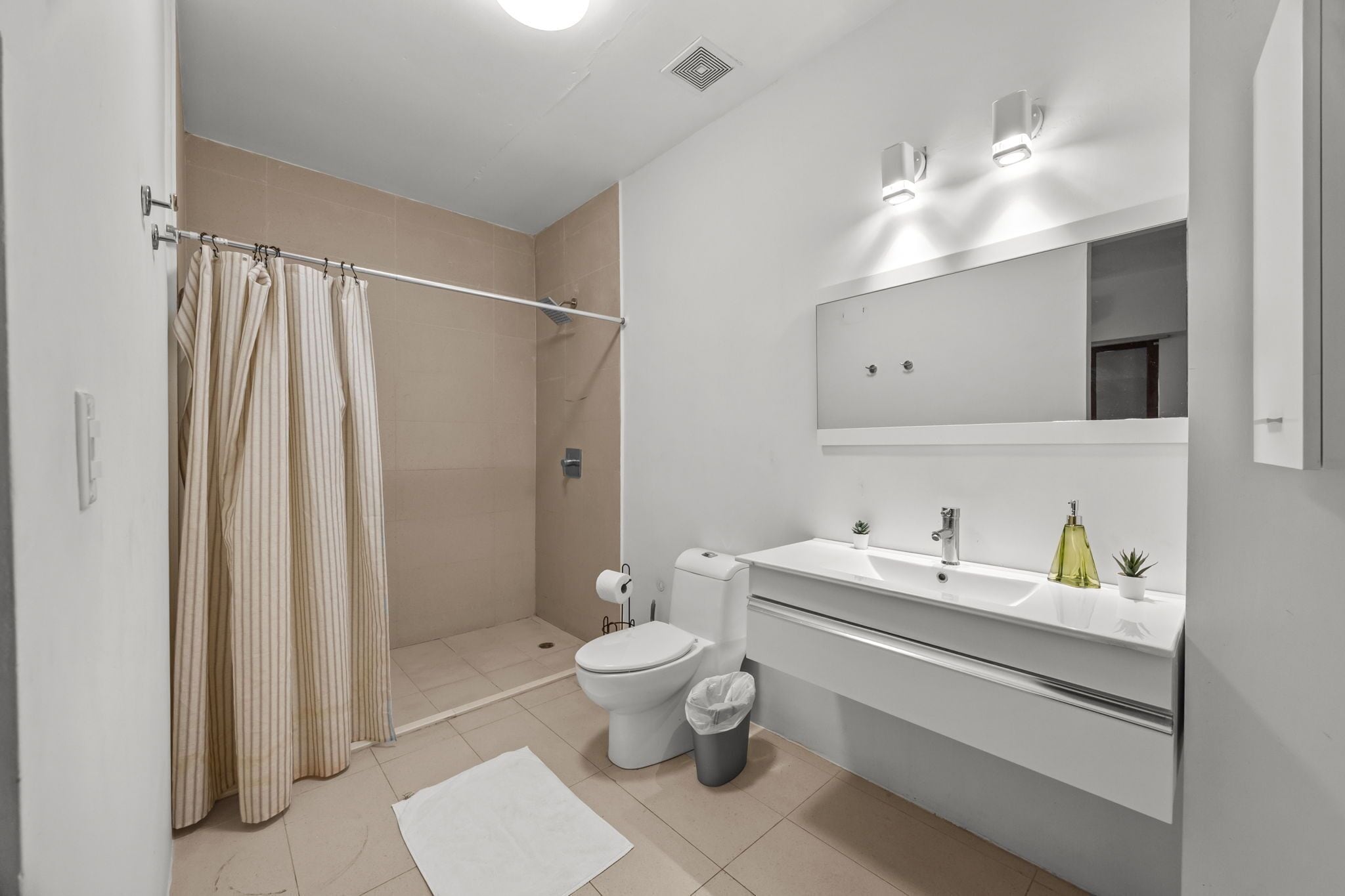 A modern bathroom with a shower, toilet, and sink.