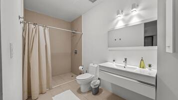 A modern bathroom with a shower, toilet, and sink.