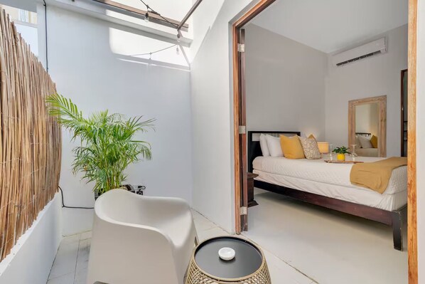 Quarto moderno com cama, mesa de cabeceira e um vaso de planta.