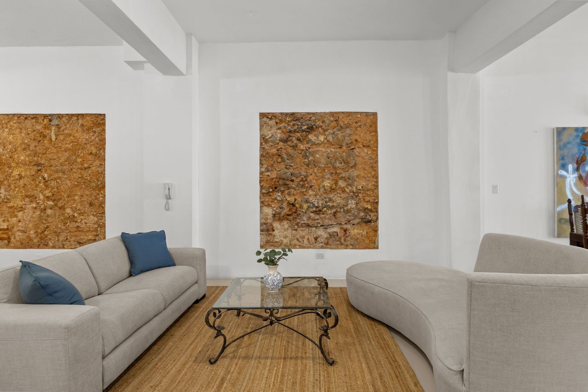 A modern living room with a sofa, armchair, coffee table, and abstract wall art.