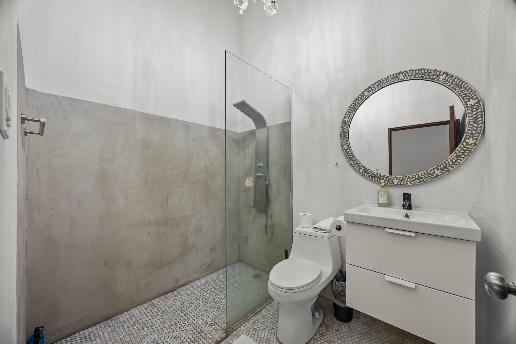 Un baño con ducha envuelta en vidrio, inodoro y lavabo con espejo superior.