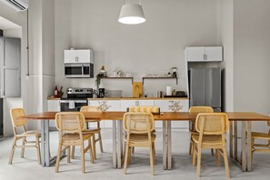 A modern kitchen with a wooden dining table and chairs, a built-in oven, and a refrigerator. - La Estadía (San Juan)