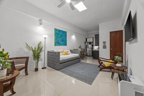A modern living room with a grey sofa, a dining table, and a kitchen area in the background. - La Estadía (San Juan)